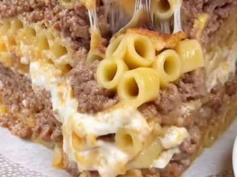 Golden-brown baked pastitsio in a baking dish showing thick layers of bucatini, spiced beef, and béchamel.