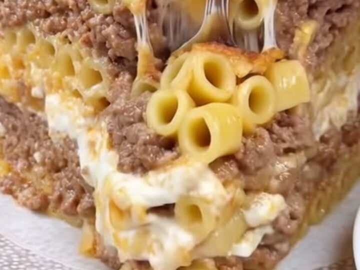 Golden-brown baked pastitsio in a baking dish showing thick layers of bucatini, spiced beef, and béchamel.