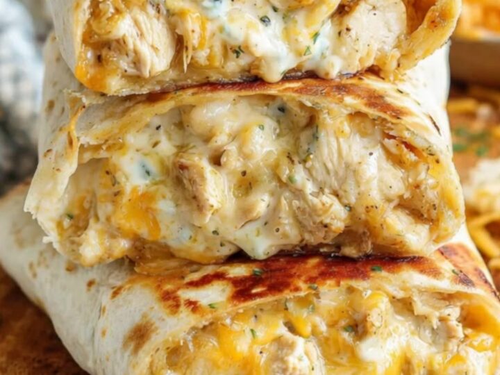 A stack of golden-brown cheesy chicken wraps on a rustic wooden board with steam rising.