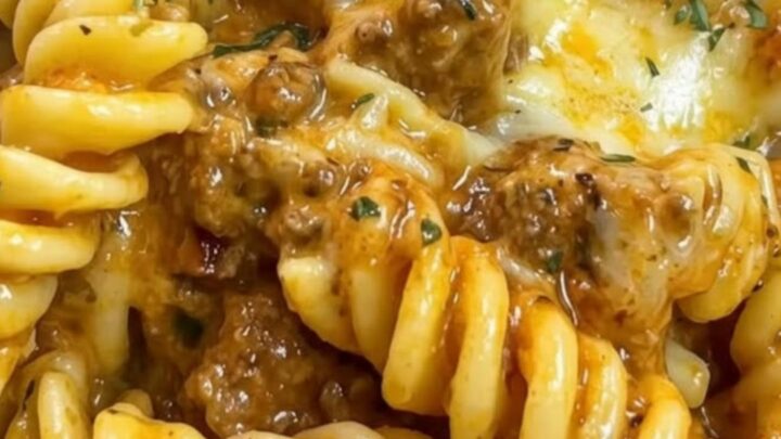 A close-up of creamy rotini pasta with ground beef and melted cheese in a large skillet.