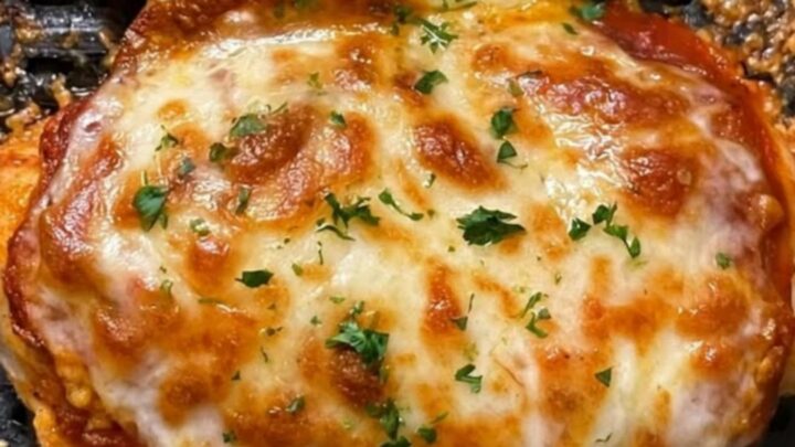 A golden-brown air fryer stuffed chicken breast on a white plate with melted mozzarella stretching out.