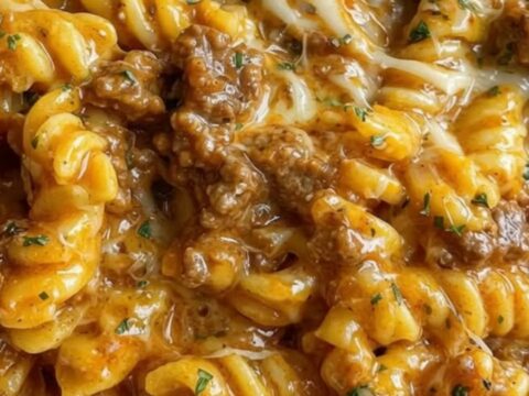 A large bowl filled with cheesy beef rotini showing melted cheese strings.