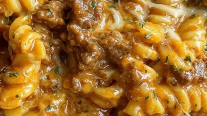 A large bowl filled with cheesy beef rotini showing melted cheese strings.