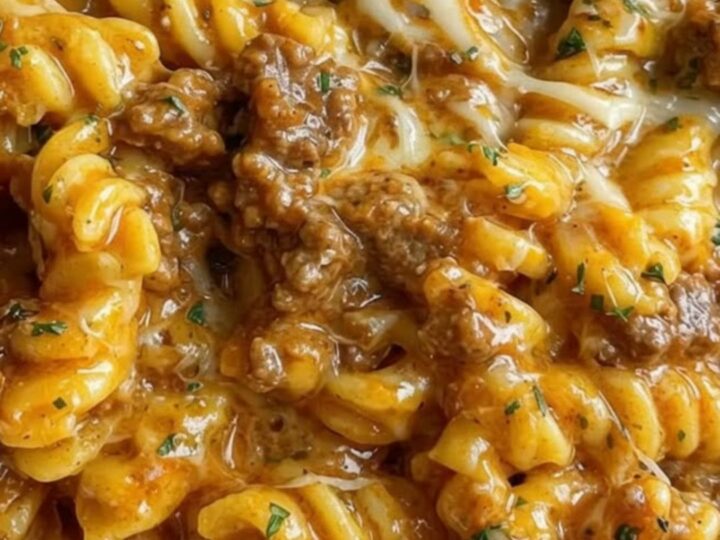 A large bowl filled with cheesy beef rotini showing melted cheese strings.