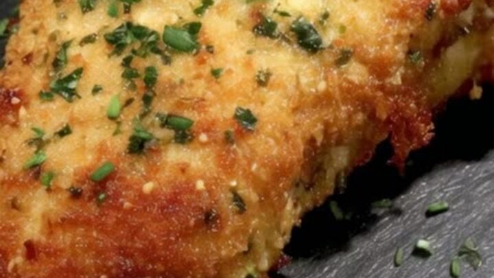 Golden-brown herb-crusted chicken cordon bleu served on a slate board.