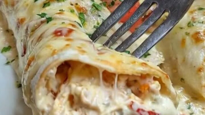 A close-up of a creamy queso chicken enchilada being lifted from a baking dish with a spatula.