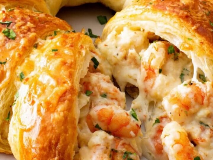 A golden, parsley-topped seafood crescent ring served on a white platter on a cozy kitchen counter.