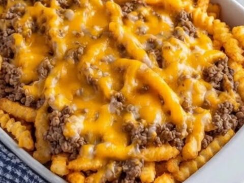 A white baking dish filled with a cheesy ground beef and french fry casserole.