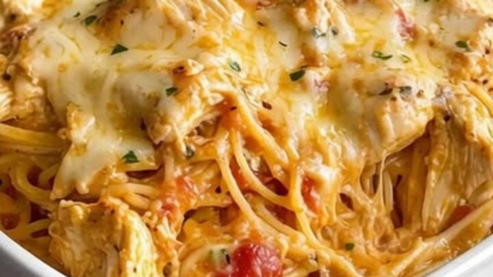 A golden, bubbling cheesy chicken spaghetti in a white baking dish.