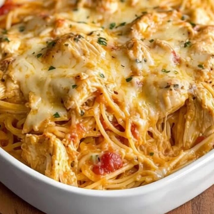 A golden, bubbling cheesy chicken spaghetti in a white baking dish.