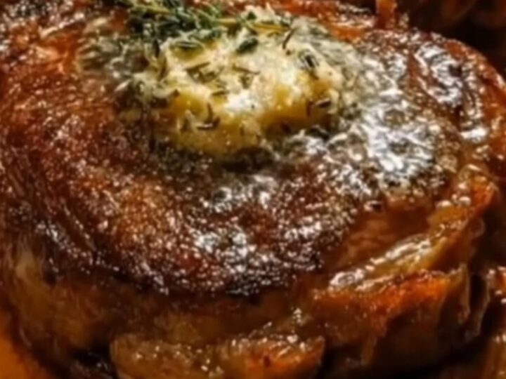 Two thick seared garlic butter steaks resting on a wooden board topped with melting butter and fresh thyme.