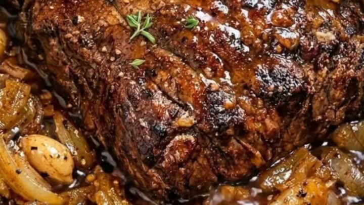 A tender, slow-cooked beef roast served on a white plate with rich onion gravy.