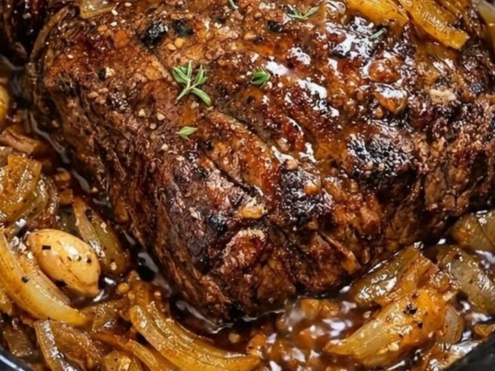 A tender, slow-cooked beef roast served on a white plate with rich onion gravy.