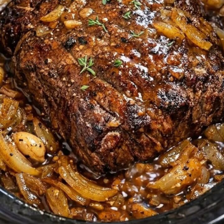 A tender, slow-cooked beef roast served on a white plate with rich onion gravy.