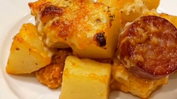 A golden, bubbly potato and sausage bake in a glass dish, fresh from the oven with melted cheese.