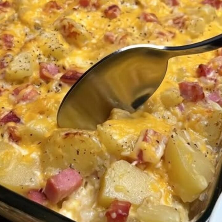 A steaming, golden-brown cheesy ham and potato casserole in a glass baking dish.