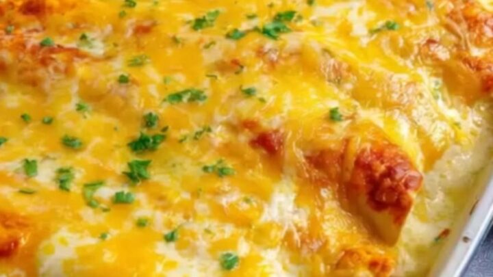 A close-up of a bubbling, cheesy chicken enchilada being lifted from a ceramic baking dish.