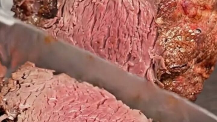 A golden-crusted standing rib roast resting on a wooden carving board.