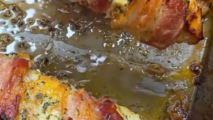 A golden, bacon-wrapped stuffed chicken breast on a plate with melted cheese visible.