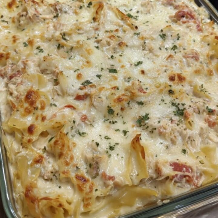 A steaming, golden-brown chicken spaghetti lasagna bake in a glass dish with melted cheese.
