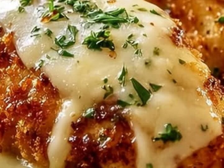 Golden Parmesan crusted chicken breast served on a white plate.