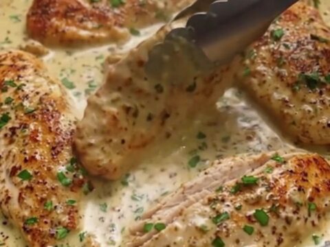 Golden seared chicken breast pieces resting in a creamy garlic butter sauce in a skillet.