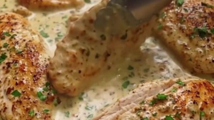 Golden seared chicken breast pieces resting in a creamy garlic butter sauce in a skillet.