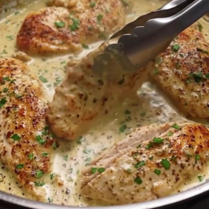 Golden seared chicken breast pieces resting in a creamy garlic butter sauce in a skillet.