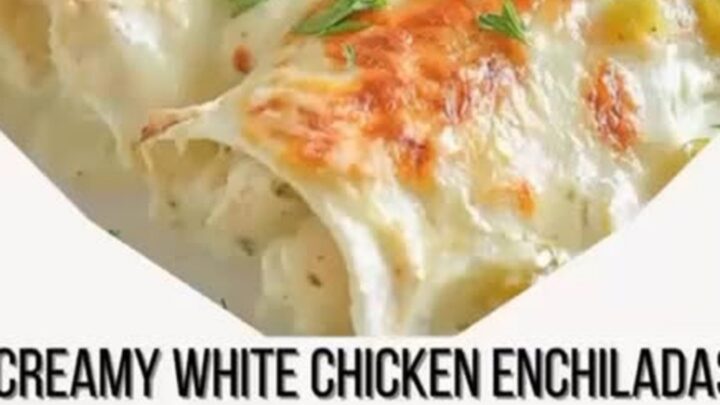 A close-up of creamy white chicken enchiladas in a baking dish with a cheese pull.