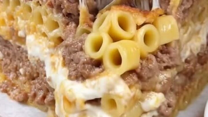 A towering slice of Greek pastitsio with clear layers of pasta, spiced beef, and a browned béchamel crust