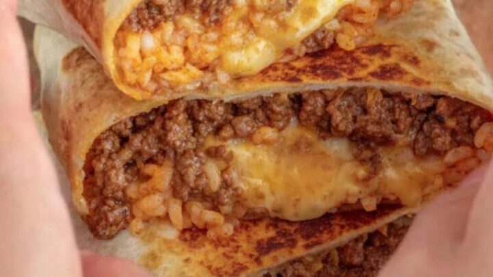 A golden-toasted grilled cheese burrito resting on a wooden board with a visible crispy cheese crust.