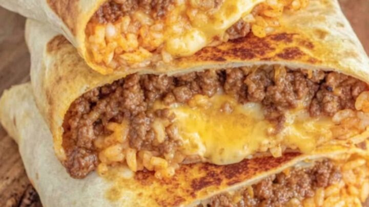 A golden-grilled burrito sliced in half, showing melted cheese and seasoned beef on a wooden board.