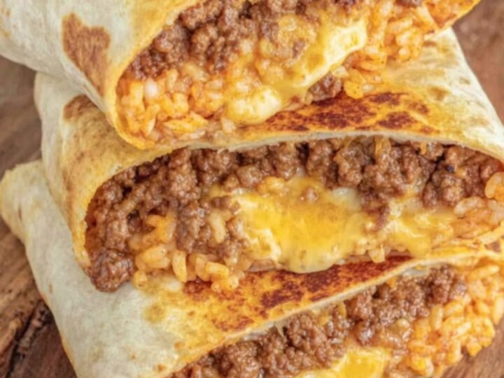 A golden-grilled burrito sliced in half, showing melted cheese and seasoned beef on a wooden board.