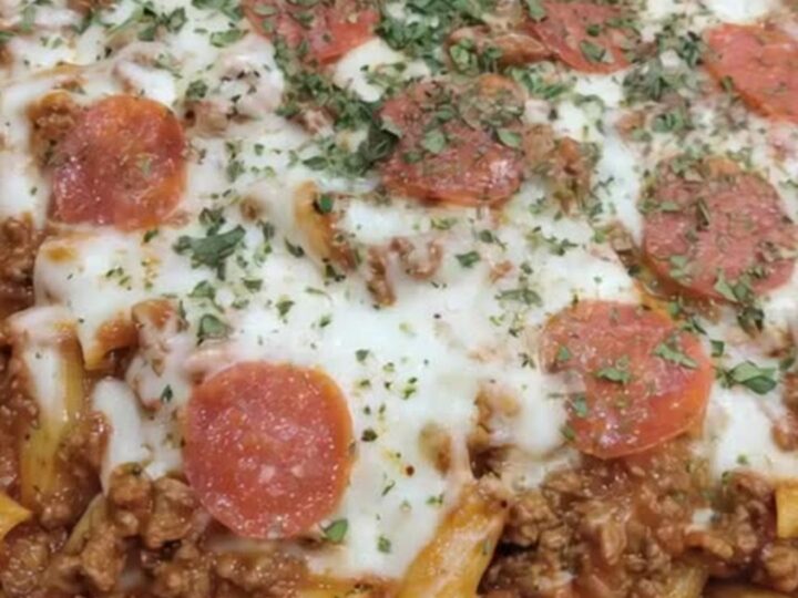 A steaming cast-iron skillet filled with Cheesy Pizza Hamburger Helper topped with pepperoni.