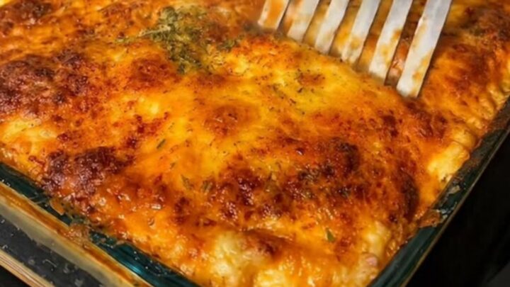 A golden, bubbling slice of baked beef lasagna served on a white ceramic plate.