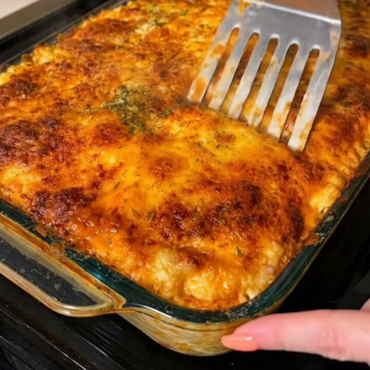A golden, bubbling slice of baked beef lasagna served on a white ceramic plate.