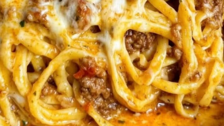 A close-up of a white bowl filled with creamy garlic cheddar beef spaghetti with a visible cheese pull.
