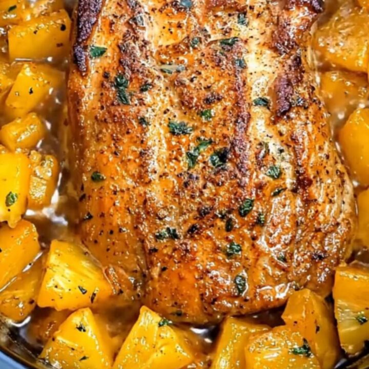 Slices of tender, succulent glazed pork loin surrounded by bubbling pineapple chunks in a slow cooker.