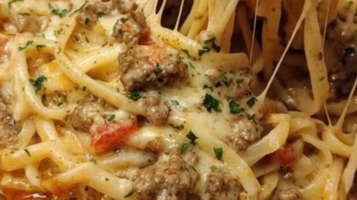 A steaming portion of creamy garlic butter beef linguine with a visible cheese pull on a white plate.