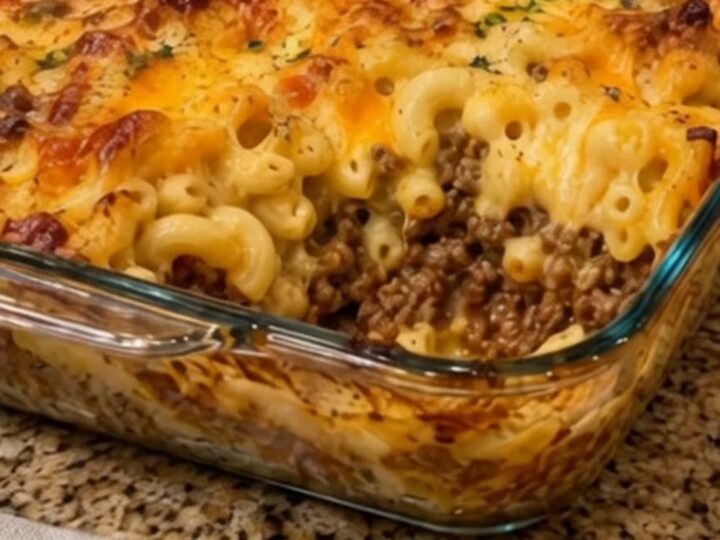 Golden, bubbly baked macaroni and cheese with ground beef inside a glass casserole dish.