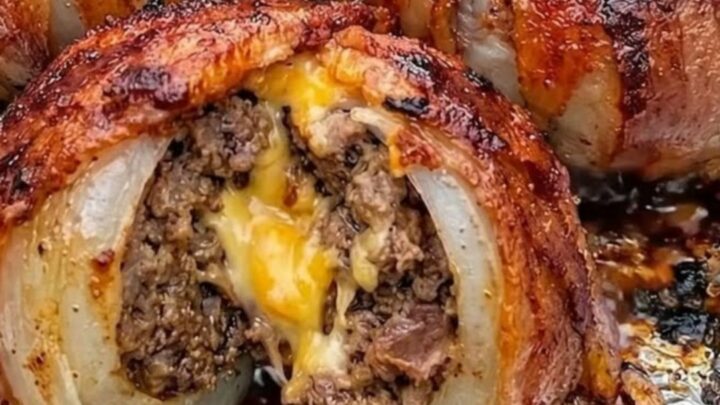 Golden, bacon-wrapped onion bombs fresh from the oven on a baking sheet.