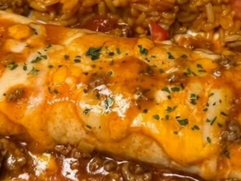 A warm, cheesy beef enchilada bake in a glass dish with a rich, stringy cheese pull.