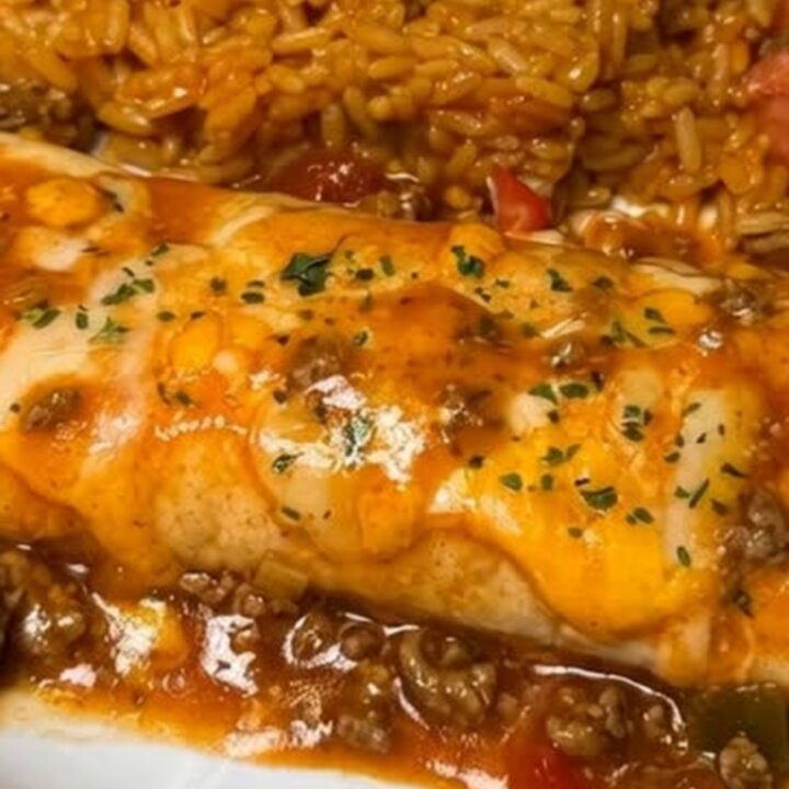 A warm, cheesy beef enchilada bake in a glass dish with a rich, stringy cheese pull.