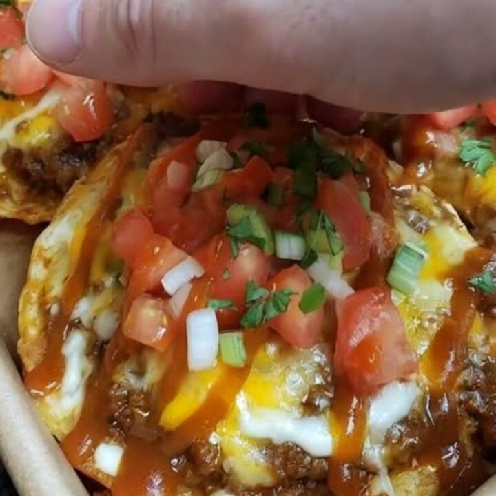 A crispy Mexican pizza on a baking sheet, topped with melted cheese, diced tomatoes, and green onions.