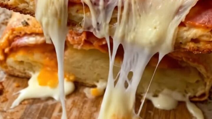 A golden-brown pepperoni stromboli being sliced on a piece of parchment paper.