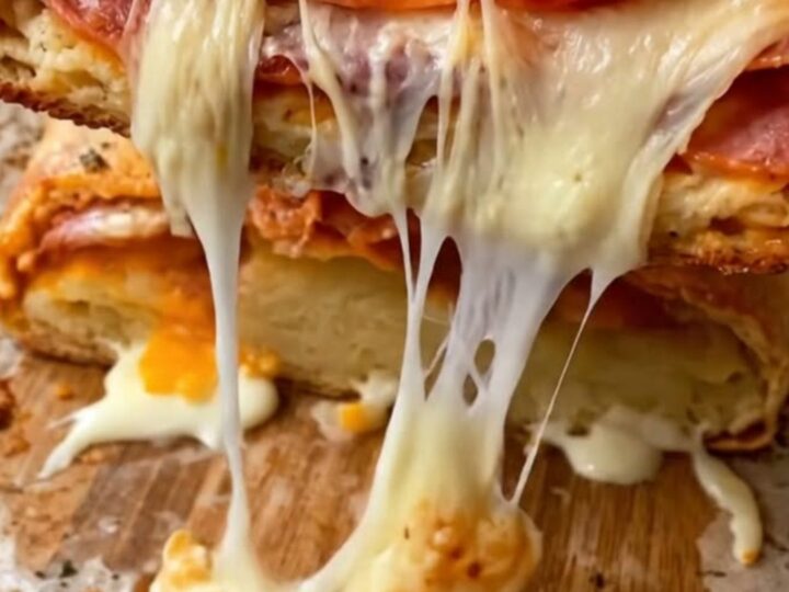 A golden-brown pepperoni stromboli being sliced on a piece of parchment paper.