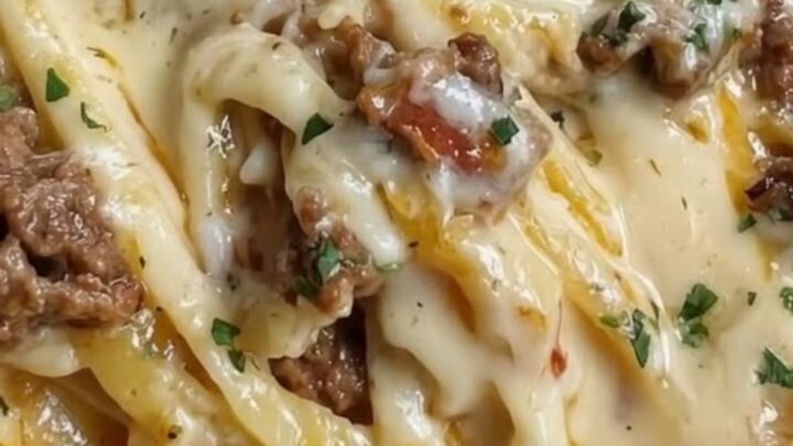 A steaming plate of creamy garlic butter beef linguine with visible cheese pulls.