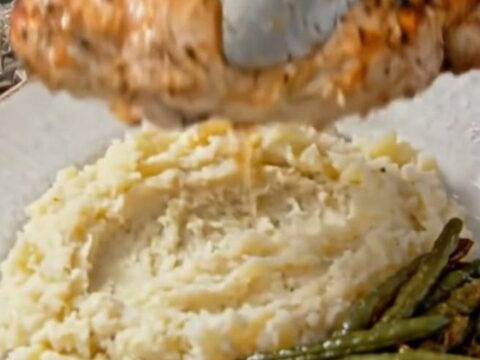 A close-up of tender, herb-seasoned chicken breast sitting in a foil packet with juices.