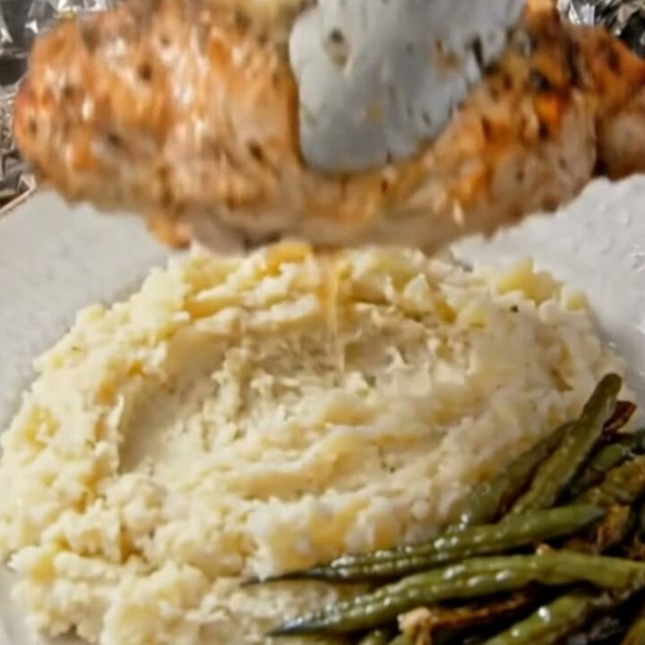 A close-up of tender, herb-seasoned chicken breast sitting in a foil packet with juices.