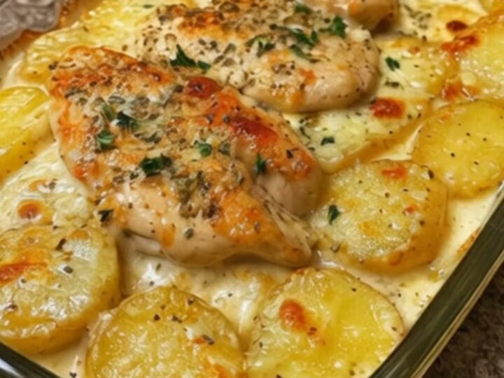 A clear glass baking dish filled with creamy chicken and golden potato coins, bubbling in a rich, cheesy sauce.